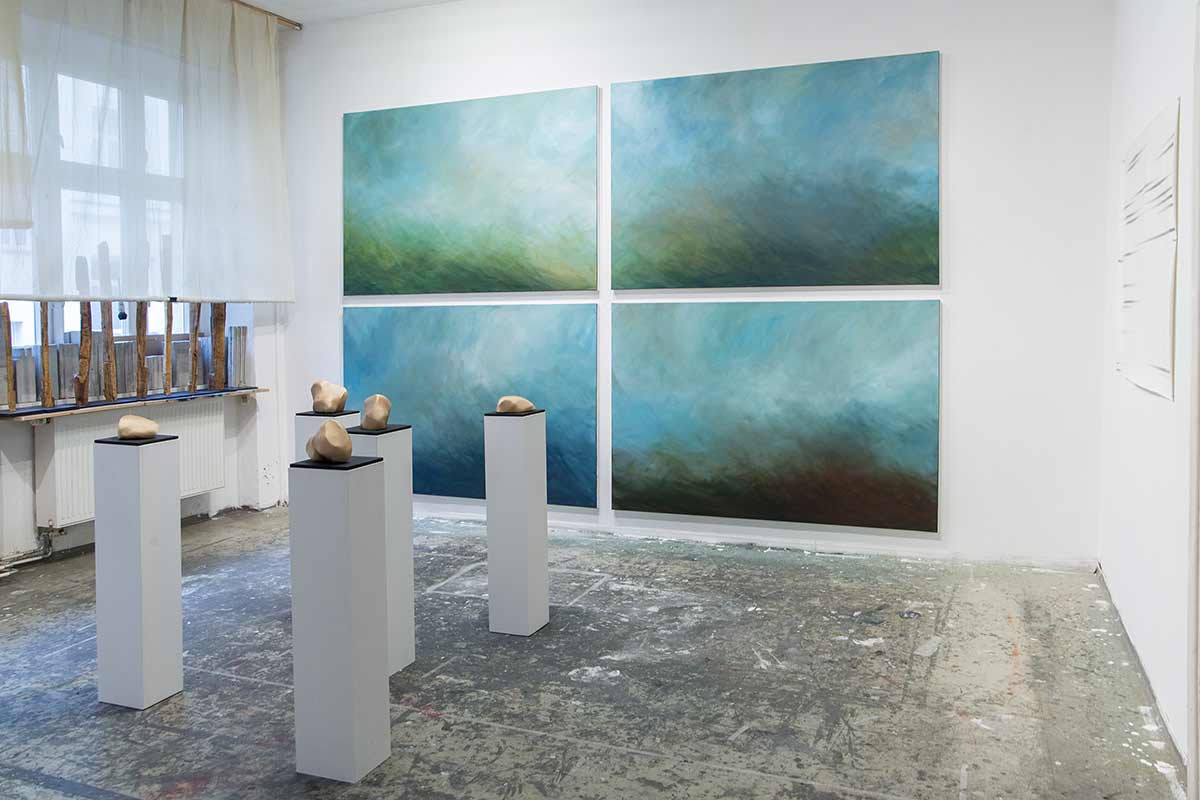 four abstract paintings with organic sculptures on pedestals