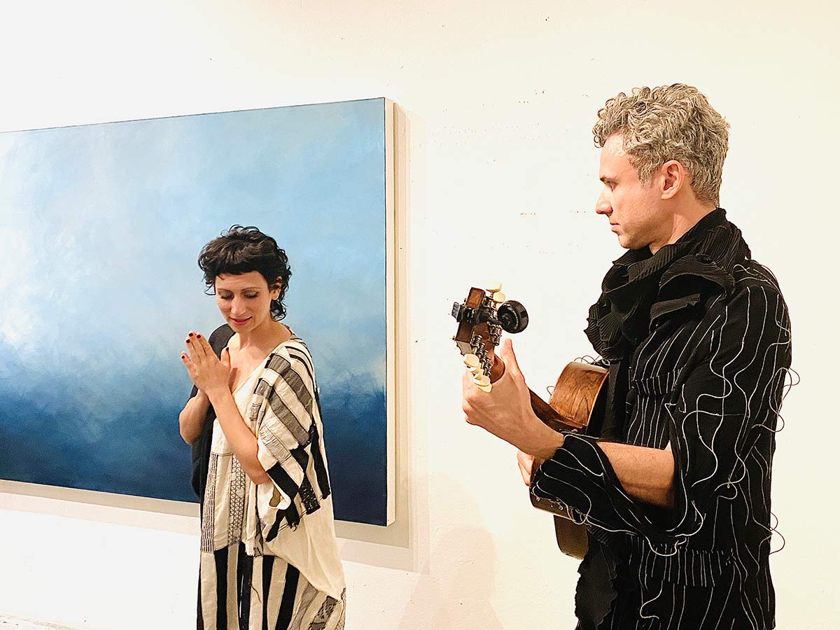 two musicians infront of an abstract blue painting